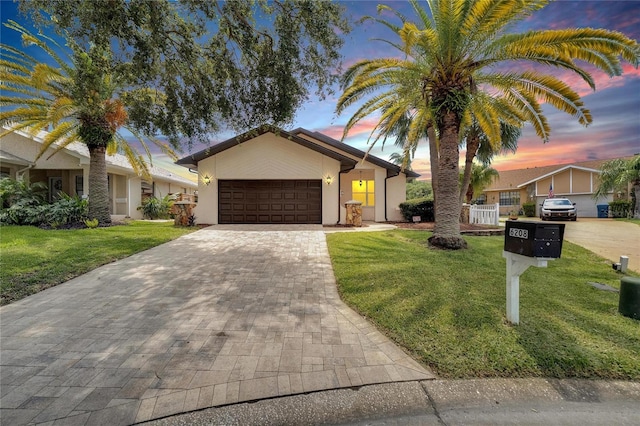 single story home featuring a garage and a lawn