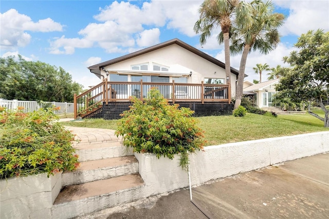 view of front facade featuring a wooden deck and a front yard