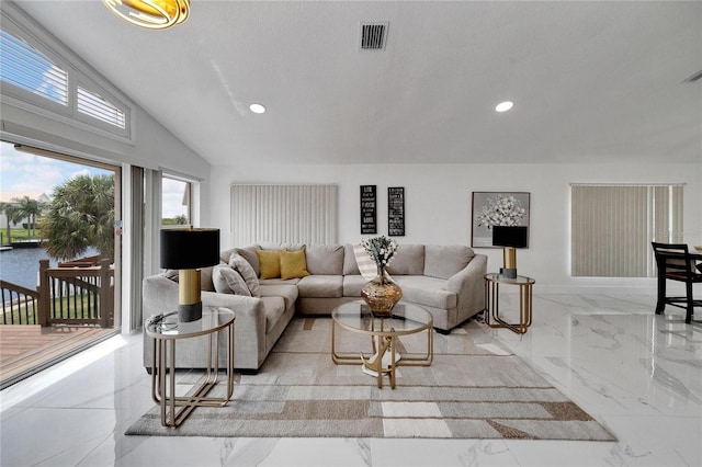 living room featuring vaulted ceiling, a water view, and a textured ceiling