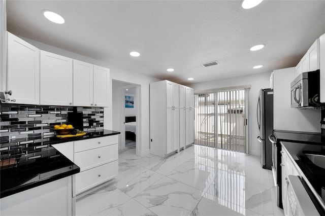 kitchen featuring appliances with stainless steel finishes, decorative backsplash, and white cabinets