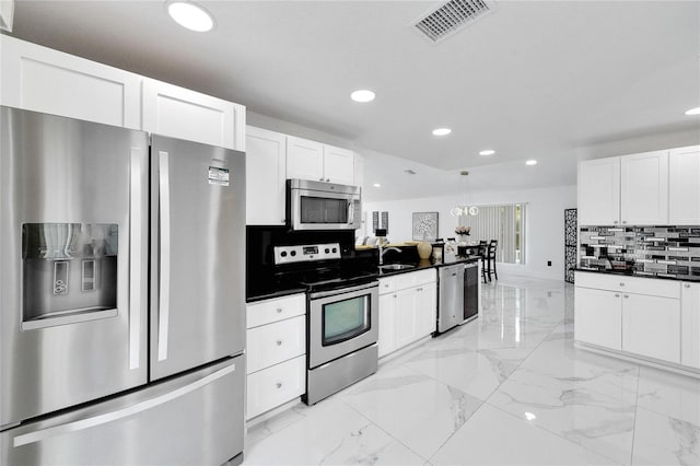 kitchen featuring sink, white cabinetry, decorative light fixtures, appliances with stainless steel finishes, and decorative backsplash