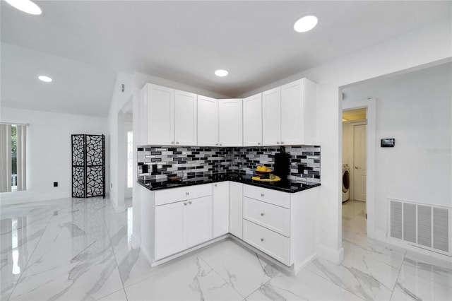 kitchen featuring washer / clothes dryer, white cabinetry, and backsplash