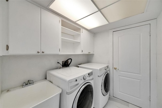 clothes washing area featuring washer and dryer, sink, and cabinets