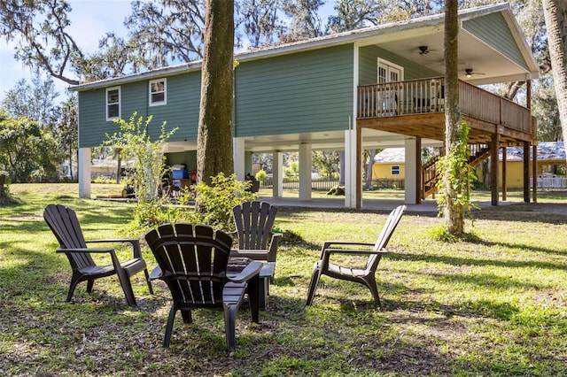 rear view of house with a deck, ceiling fan, and a lawn