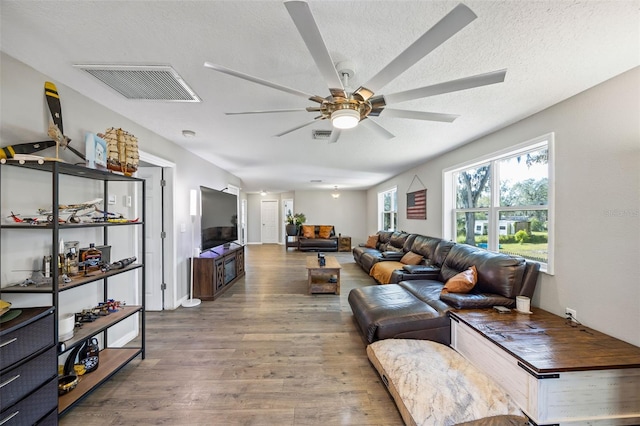 living room with ceiling fan, wood-type flooring, and a textured ceiling