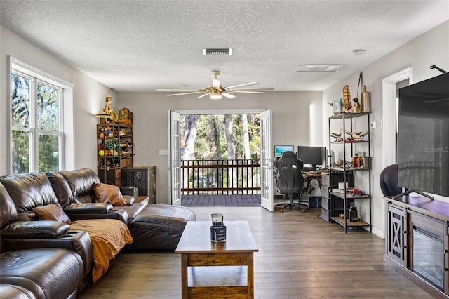 living room with dark hardwood / wood-style floors, ceiling fan, and a textured ceiling