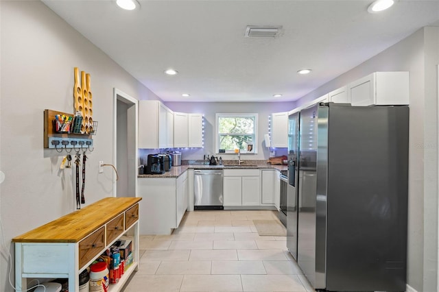 kitchen with dark stone countertops, white cabinetry, sink, and appliances with stainless steel finishes