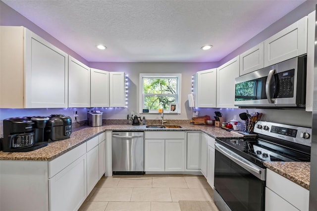 kitchen featuring stone counters, sink, stainless steel appliances, a textured ceiling, and white cabinets