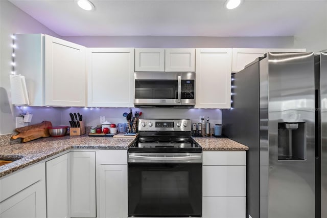 kitchen with white cabinetry, stainless steel appliances, and stone countertops