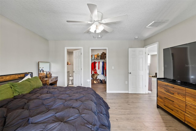 bedroom with connected bathroom, ceiling fan, a spacious closet, hardwood / wood-style floors, and a closet