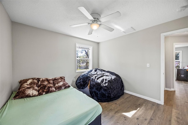 bedroom featuring hardwood / wood-style floors, ceiling fan, and a textured ceiling