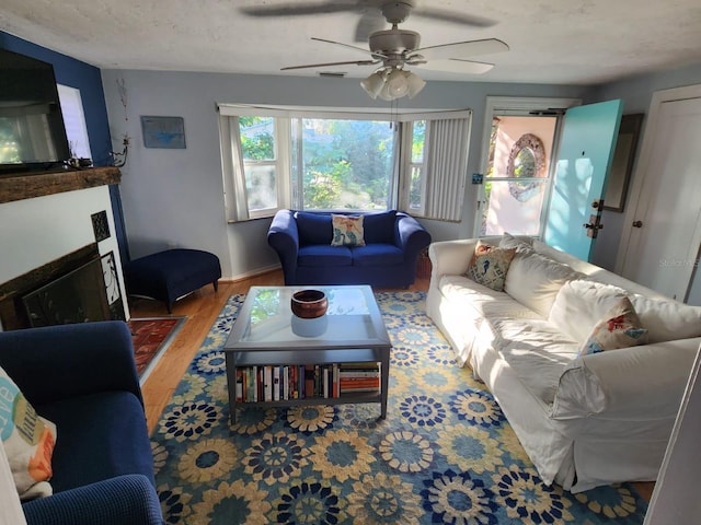 living room with hardwood / wood-style flooring, ceiling fan, and a textured ceiling