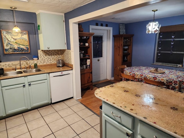 kitchen featuring dishwasher, light tile patterned floors, sink, and hanging light fixtures