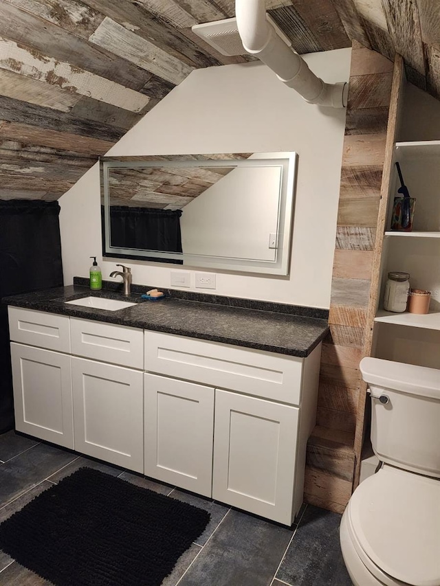 bathroom with toilet, tile patterned floors, vanity, and vaulted ceiling