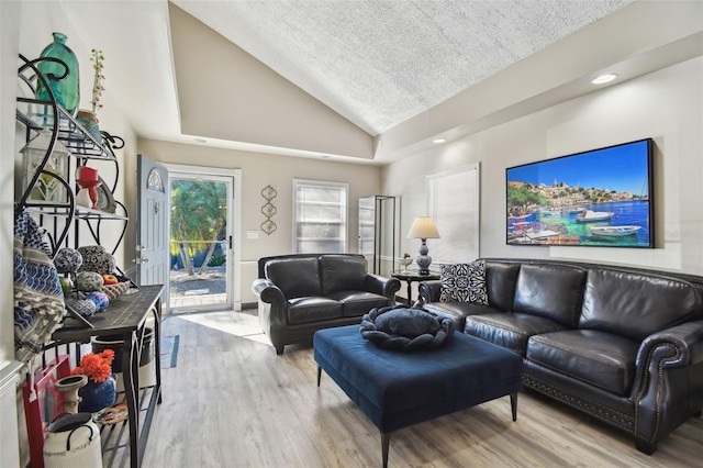 living room with a textured ceiling, light hardwood / wood-style flooring, and vaulted ceiling