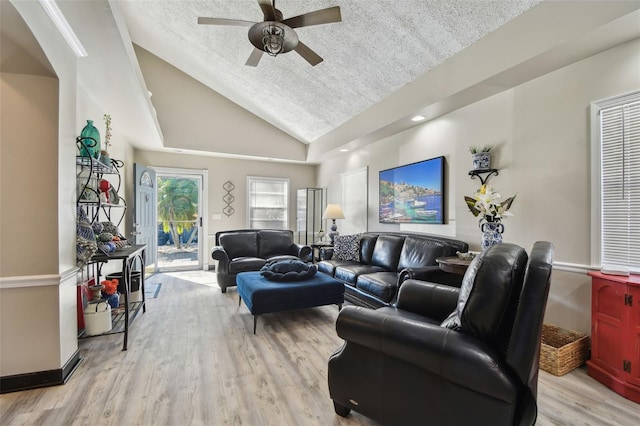 living room with a textured ceiling, ceiling fan, light hardwood / wood-style floors, and lofted ceiling