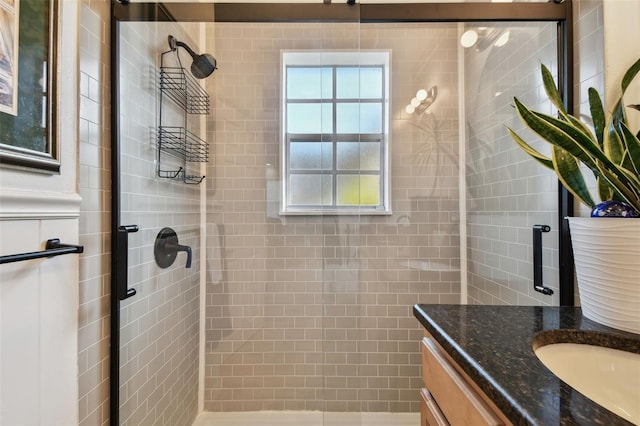 bathroom featuring vanity, a healthy amount of sunlight, and a shower with shower door