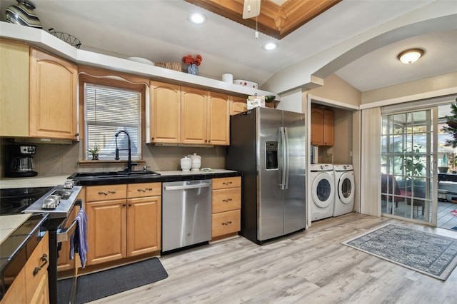 kitchen with appliances with stainless steel finishes, washing machine and dryer, backsplash, and sink