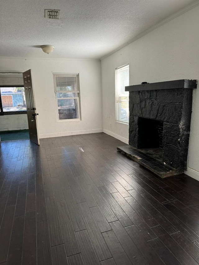 unfurnished living room featuring a textured ceiling, a stone fireplace, and dark hardwood / wood-style floors