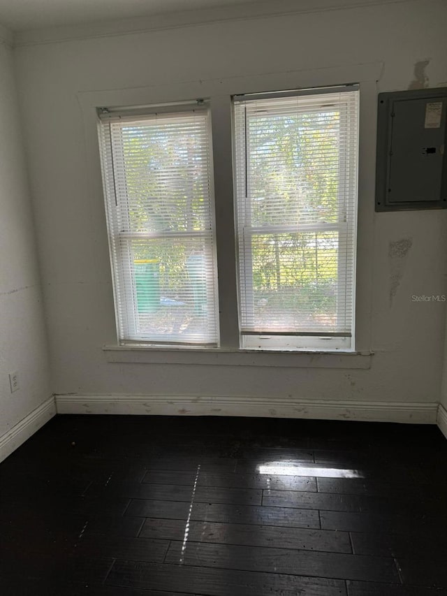 empty room featuring electric panel, crown molding, and dark hardwood / wood-style flooring