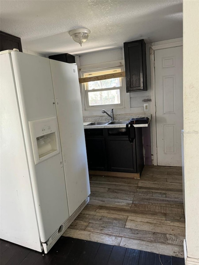 kitchen with dark hardwood / wood-style flooring, white fridge with ice dispenser, a textured ceiling, and sink