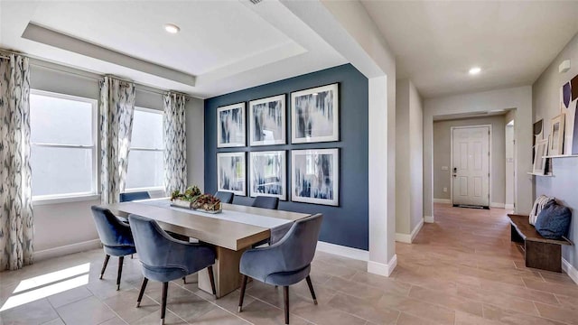 dining room featuring light tile patterned flooring and a raised ceiling