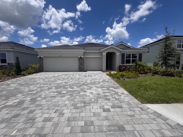 4314 Pullet Ct, Lakewood Ranch, FL 34211 - view of front of home with decorative driveway, a garage, a front lawn, stucco siding, and stone siding