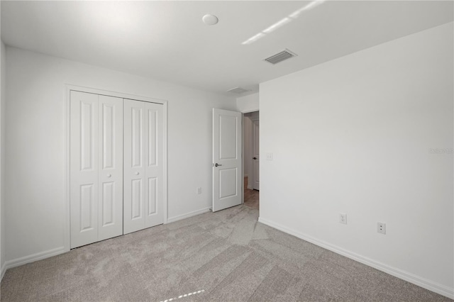 unfurnished bedroom with light colored carpet and a closet