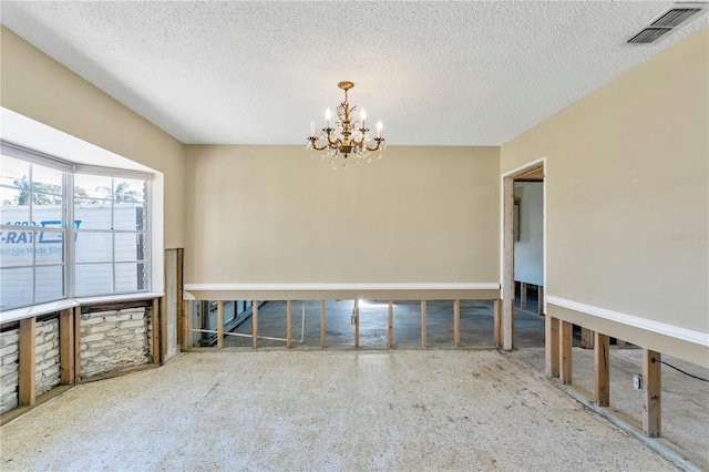 empty room featuring a textured ceiling and a notable chandelier