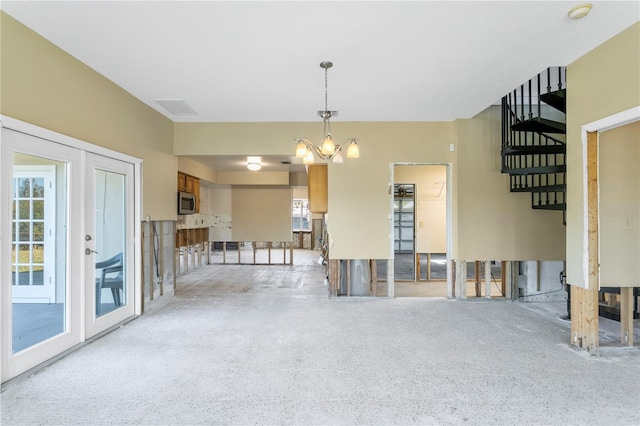 unfurnished dining area featuring french doors and a chandelier