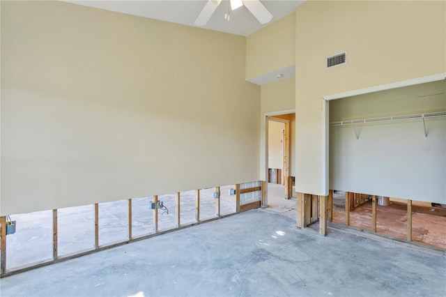 bedroom with ceiling fan, concrete flooring, and a closet