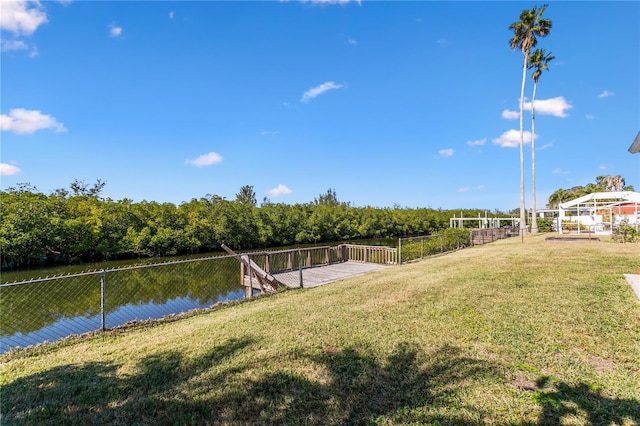 view of dock with a lawn and a water view