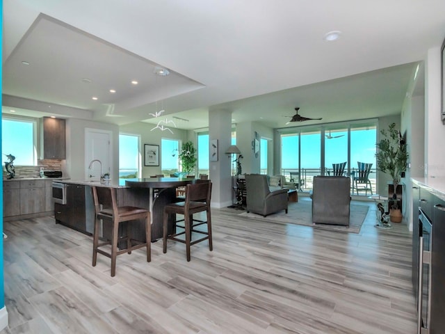 dining area featuring a wall of windows, light hardwood / wood-style floors, ceiling fan, and sink