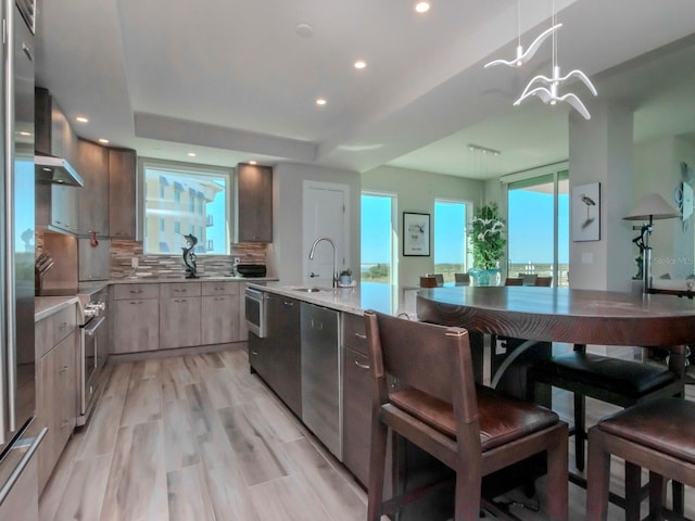 kitchen featuring stainless steel range with electric cooktop, sink, hanging light fixtures, decorative backsplash, and light hardwood / wood-style floors