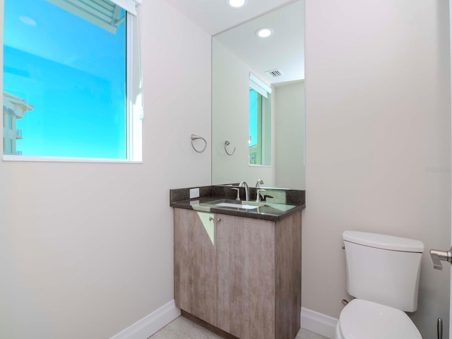 bathroom with a wealth of natural light, vanity, and toilet