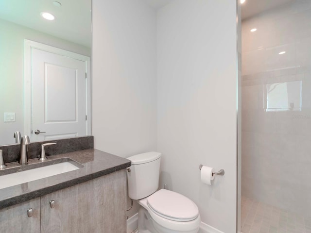 bathroom featuring tiled shower, vanity, and toilet