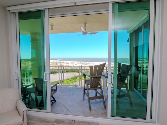 balcony with ceiling fan, a water view, and a beach view