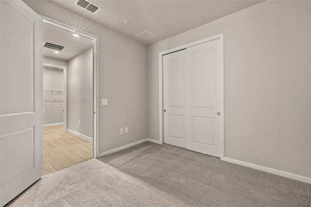 unfurnished bedroom with light carpet and a closet