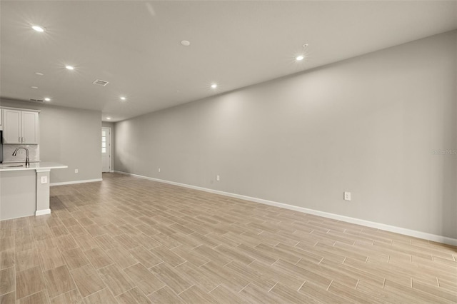 unfurnished living room with light hardwood / wood-style floors and sink