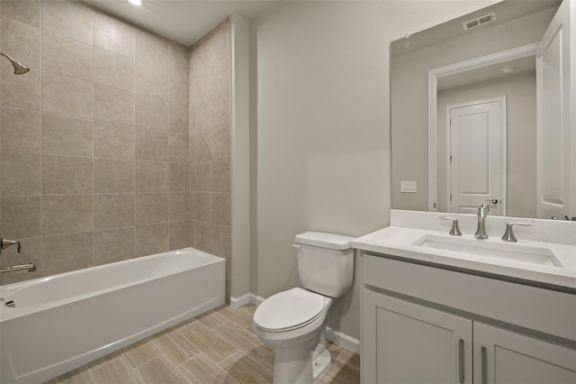 full bathroom with tiled shower / bath, vanity, and toilet