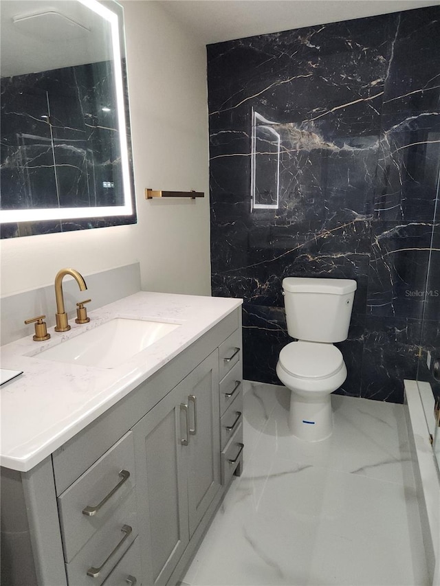 bathroom with toilet, marble finish floor, and vanity