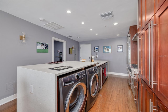 laundry room with washer and dryer, light wood-type flooring, and sink