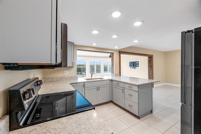 kitchen with gray cabinetry, refrigerator, sink, light tile patterned flooring, and stainless steel range oven