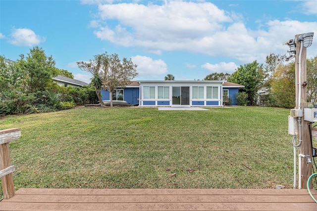 rear view of property featuring a sunroom and a yard