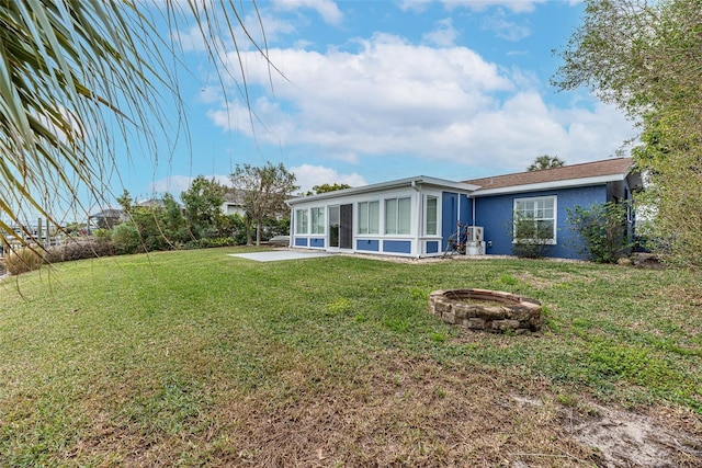 back of house with a sunroom, a fire pit, and a yard