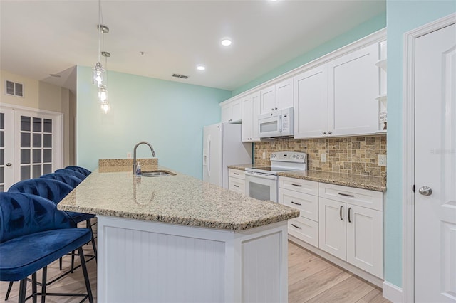 kitchen featuring a kitchen bar, white appliances, white cabinetry, and sink