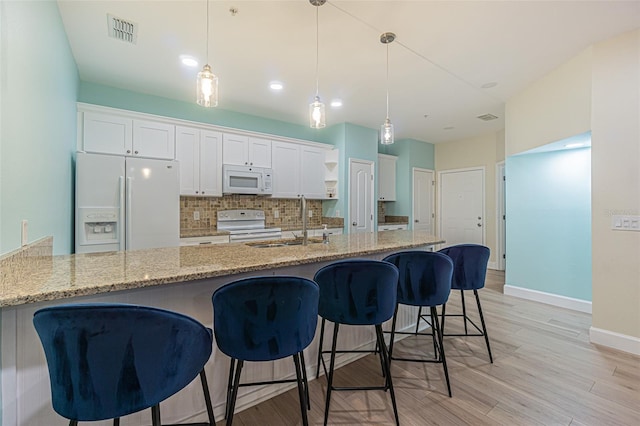 kitchen with white cabinets, white appliances, and hanging light fixtures