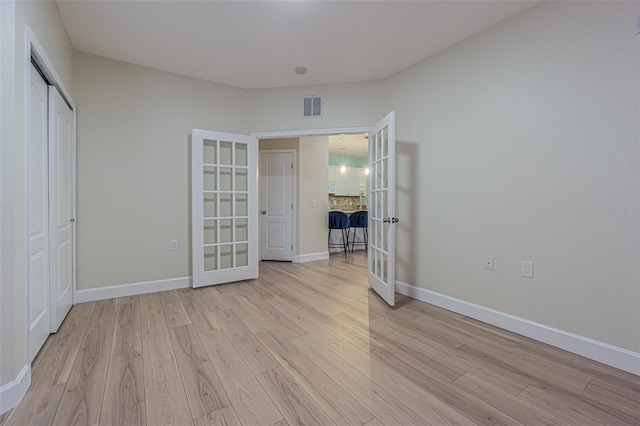 unfurnished bedroom featuring a closet, french doors, and light hardwood / wood-style flooring