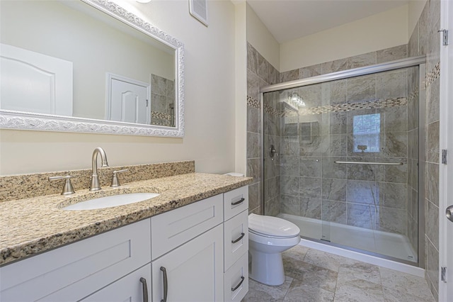 bathroom featuring a shower with door, vanity, and toilet