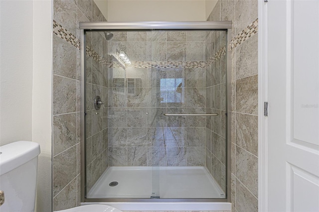 bathroom featuring toilet and a shower with shower door